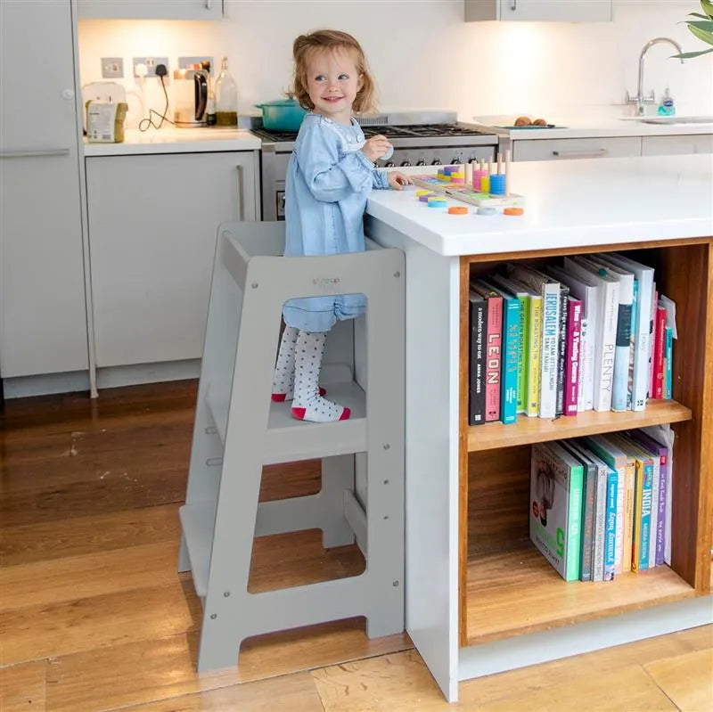 image showing a child in grey  toddler tower playing with wooden toy